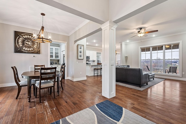 dining area featuring decorative columns, dark wood-type flooring, ceiling fan with notable chandelier, and ornamental molding