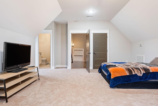 bedroom with connected bathroom, light colored carpet, and vaulted ceiling