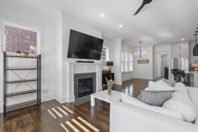 living room with dark hardwood / wood-style floors, a notable chandelier, ornamental molding, and a tiled fireplace