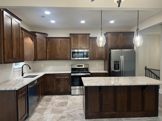 kitchen with sink, light stone counters, decorative light fixtures, dark brown cabinets, and stainless steel appliances