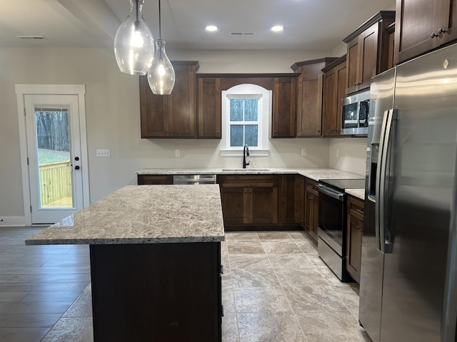 kitchen with sink, dark brown cabinets, a center island, and appliances with stainless steel finishes