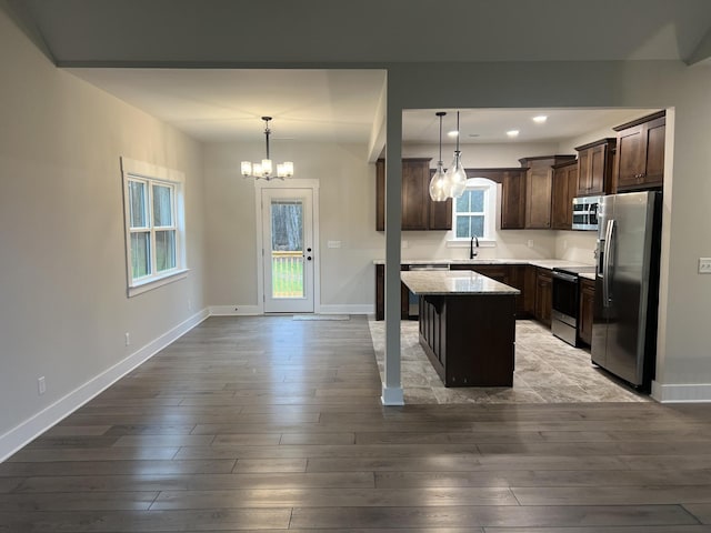 kitchen with pendant lighting, sink, stainless steel appliances, and a kitchen island