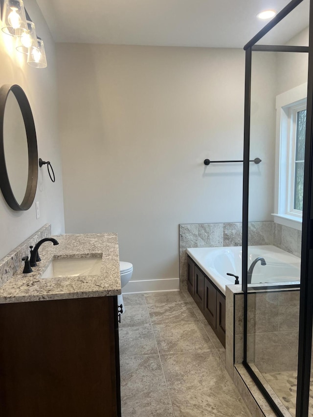 bathroom with vanity, tiled bath, and toilet