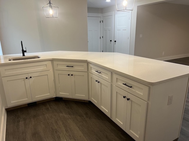 kitchen with sink, white cabinets, dark hardwood / wood-style floors, and decorative light fixtures