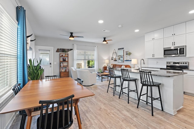 kitchen with dark stone counters, white cabinets, sink, an island with sink, and appliances with stainless steel finishes