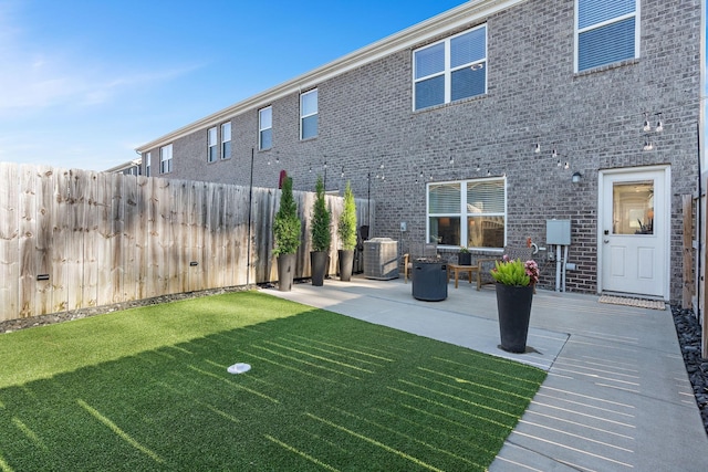 back of property with cooling unit, a patio area, and a yard