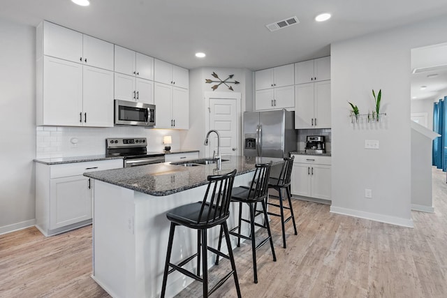 kitchen featuring white cabinets, sink, an island with sink, and stainless steel appliances