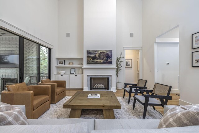 living room featuring light hardwood / wood-style floors, built in features, and a high ceiling