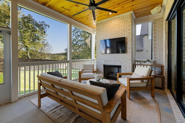 sunroom / solarium featuring wood ceiling, ceiling fan, and an outdoor brick fireplace