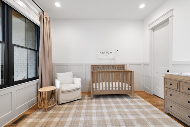 bedroom featuring a crib and light hardwood / wood-style floors