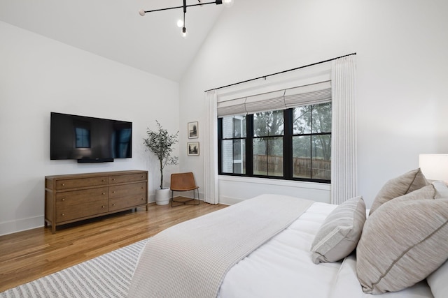 bedroom featuring high vaulted ceiling and light hardwood / wood-style floors