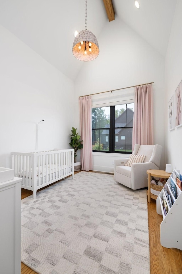 bedroom featuring high vaulted ceiling, light hardwood / wood-style flooring, a notable chandelier, beamed ceiling, and a crib