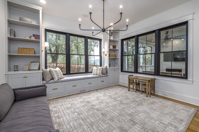 sitting room featuring an inviting chandelier, built in features, and light wood-type flooring