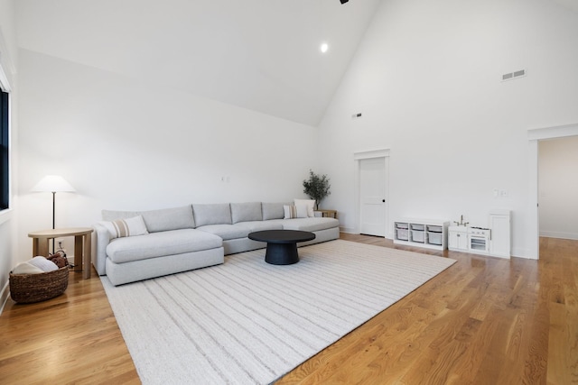 living room featuring high vaulted ceiling and light hardwood / wood-style flooring