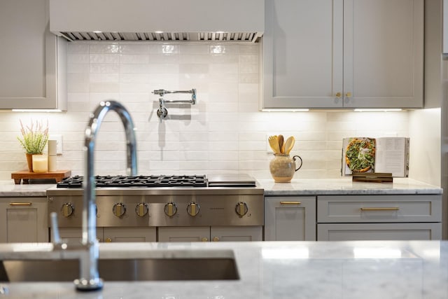 kitchen featuring decorative backsplash, gray cabinets, and light stone countertops