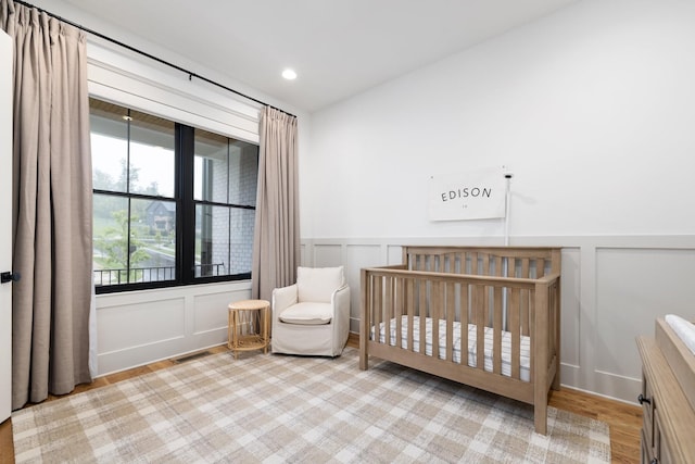 bedroom with a crib and light wood-type flooring