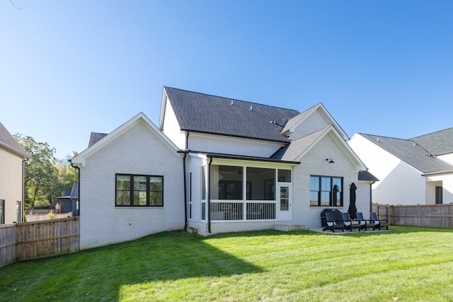 rear view of property featuring a sunroom and a lawn