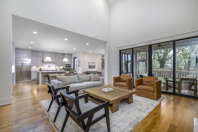 living room with a towering ceiling and light hardwood / wood-style flooring