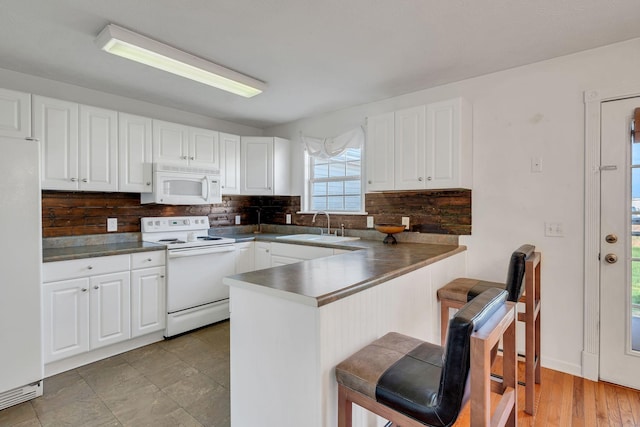 kitchen with white cabinetry, sink, white appliances, and kitchen peninsula