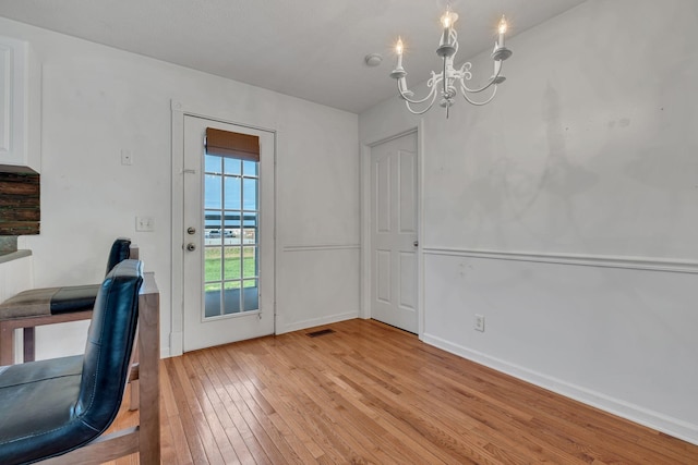 unfurnished dining area with light hardwood / wood-style floors and a notable chandelier