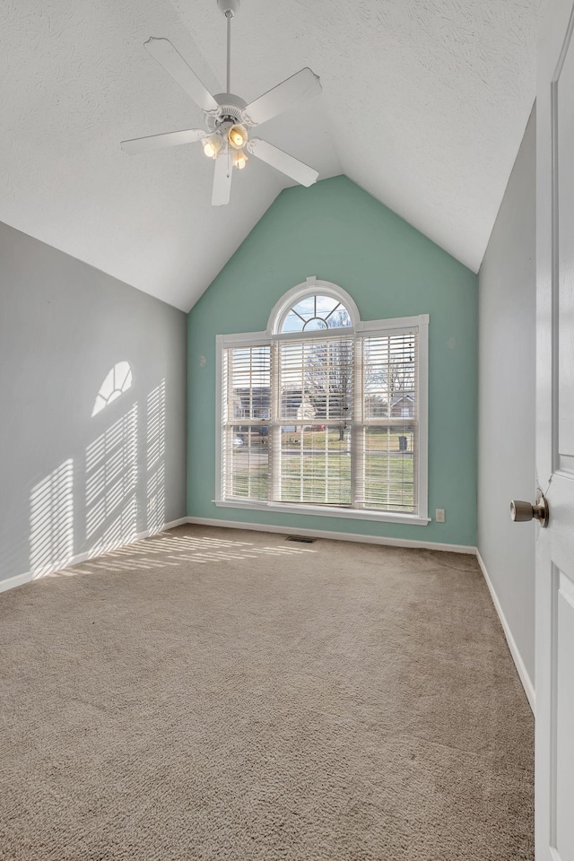 spare room featuring carpet flooring, lofted ceiling, ceiling fan, and a textured ceiling