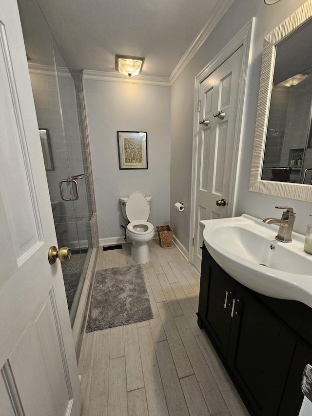 bathroom featuring crown molding, a shower with door, vanity, and toilet