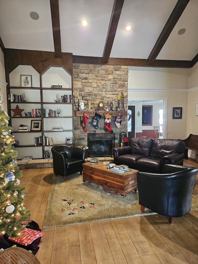 living room featuring a fireplace, wood-type flooring, built in shelves, and beam ceiling