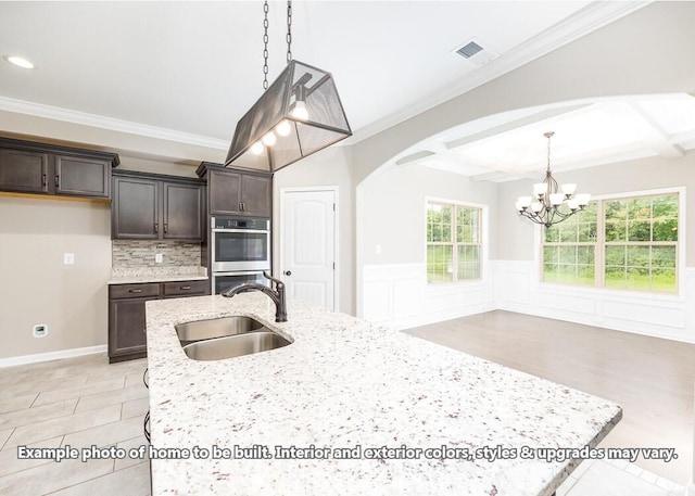 kitchen featuring dark brown cabinetry, ornamental molding, sink, and a chandelier