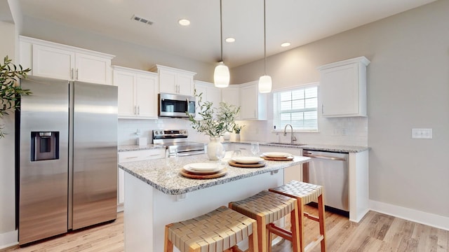 kitchen with sink, light wood-type flooring, appliances with stainless steel finishes, tasteful backsplash, and white cabinetry