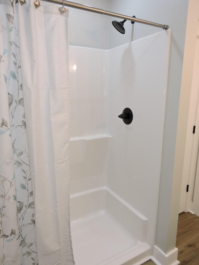 bathroom with hardwood / wood-style flooring and walk in shower