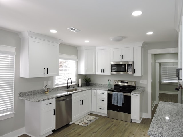 kitchen featuring light stone countertops, appliances with stainless steel finishes, light wood-type flooring, sink, and white cabinets