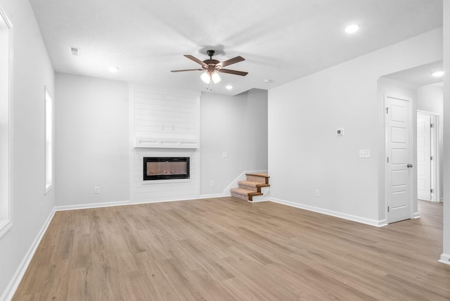 unfurnished living room featuring ceiling fan, a fireplace, and light hardwood / wood-style flooring