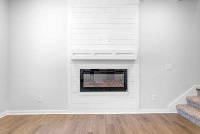 details featuring hardwood / wood-style flooring and a large fireplace