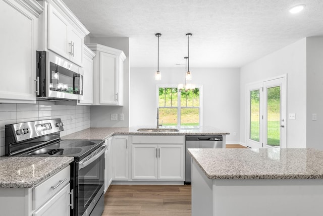 kitchen featuring decorative backsplash, stainless steel appliances, sink, wood-type flooring, and white cabinetry