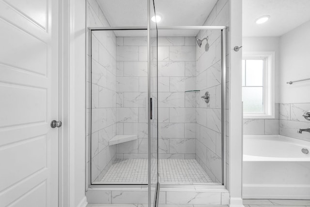 bathroom featuring shower with separate bathtub and a textured ceiling