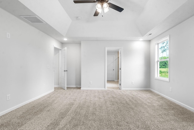 carpeted empty room featuring ceiling fan and a raised ceiling