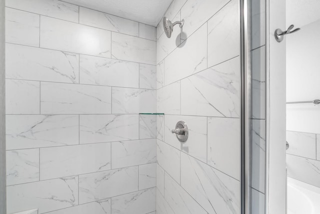 bathroom featuring tiled shower and a textured ceiling