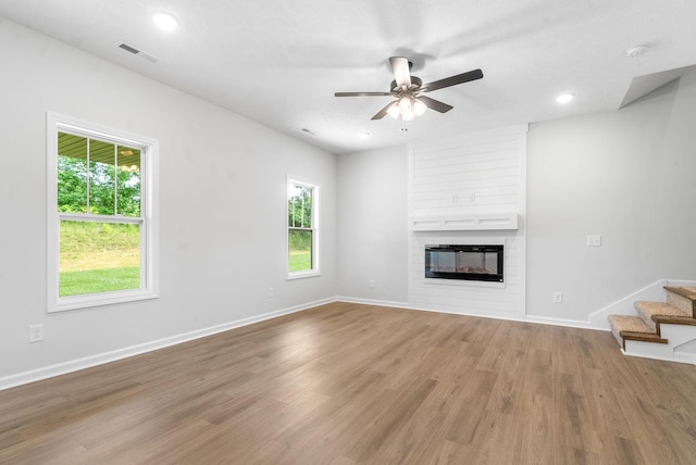 unfurnished living room with ceiling fan, a fireplace, and hardwood / wood-style flooring