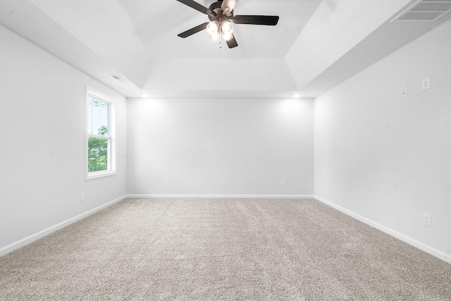 empty room with carpet flooring, a tray ceiling, and ceiling fan