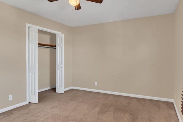 unfurnished bedroom with a closet, light colored carpet, and ceiling fan