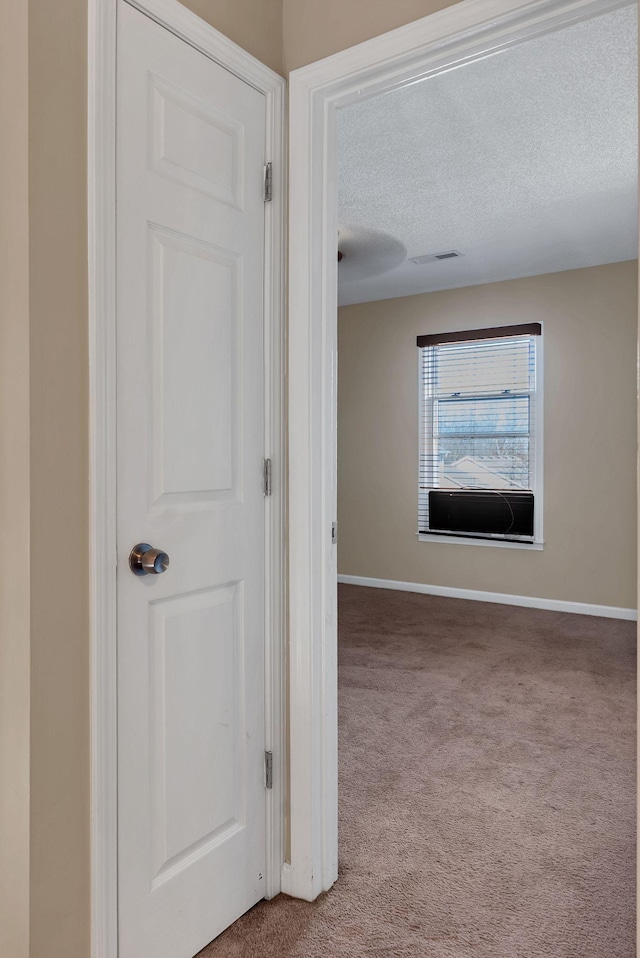 hall with light colored carpet and a textured ceiling