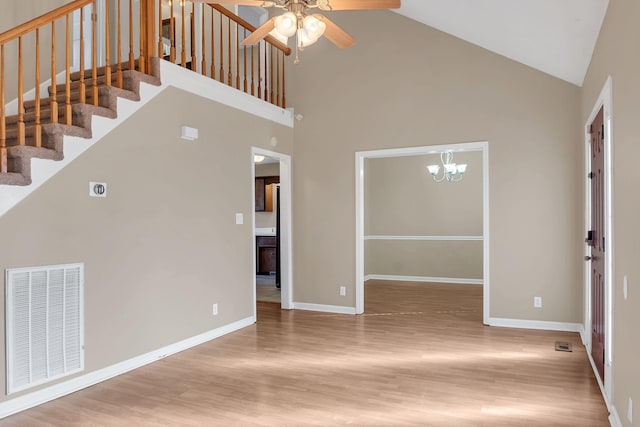 interior space featuring ceiling fan with notable chandelier, light hardwood / wood-style floors, and high vaulted ceiling