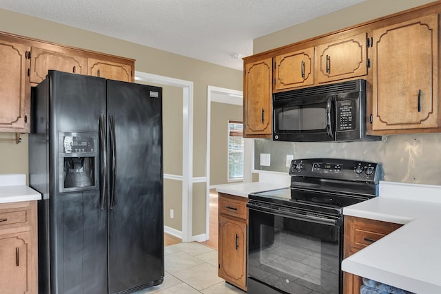 kitchen with black appliances, light tile patterned flooring, and a textured ceiling