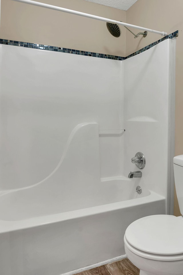 bathroom featuring hardwood / wood-style floors, shower / bathtub combination, and toilet