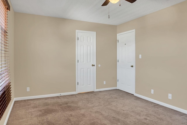 empty room with carpet flooring, ceiling fan, a fireplace, and a textured ceiling