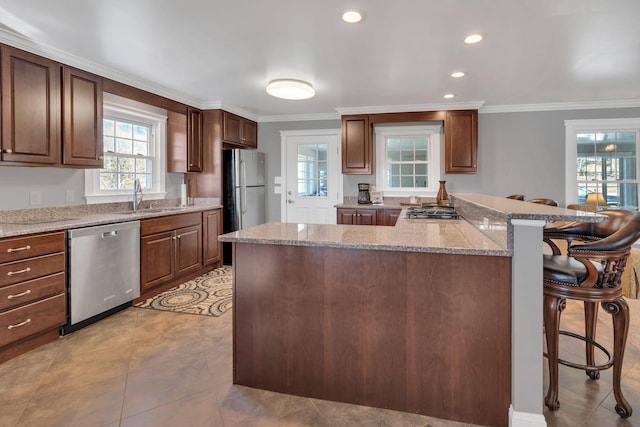 kitchen with a kitchen breakfast bar, sink, ornamental molding, and stainless steel appliances