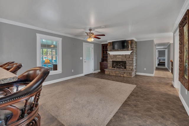 living room with dark tile patterned floors, a stone fireplace, ceiling fan, and crown molding