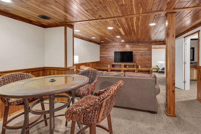 dining room with light colored carpet, wooden ceiling, and wooden walls