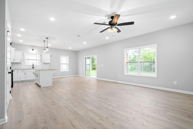 unfurnished living room featuring light wood-type flooring, ceiling fan, and sink