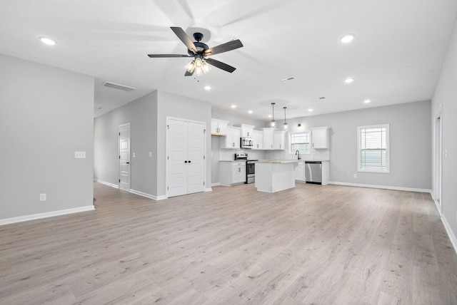 unfurnished living room featuring ceiling fan, light hardwood / wood-style floors, and sink